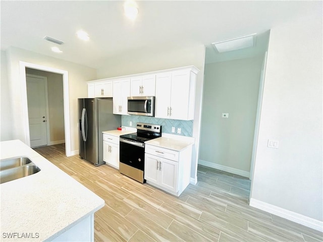 kitchen featuring wood finish floors, visible vents, white cabinets, appliances with stainless steel finishes, and backsplash