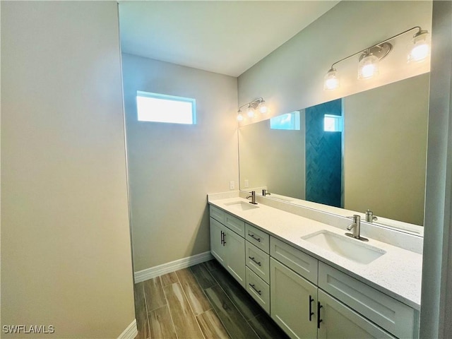 bathroom featuring double vanity, wood tiled floor, baseboards, and a sink