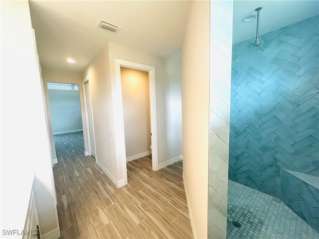 corridor featuring baseboards, visible vents, and wood tiled floor