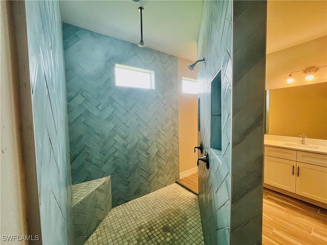 bathroom featuring wood finished floors, a tile shower, and vanity