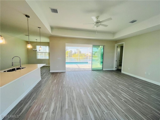 unfurnished living room with visible vents, a sink, baseboards, and wood finished floors