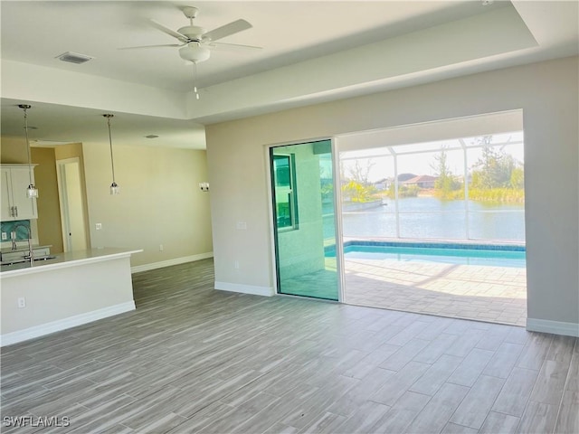 unfurnished living room with a ceiling fan, visible vents, baseboards, and wood finished floors