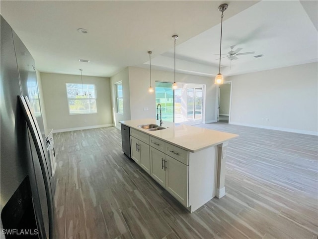 kitchen featuring open floor plan, light countertops, a sink, and an island with sink