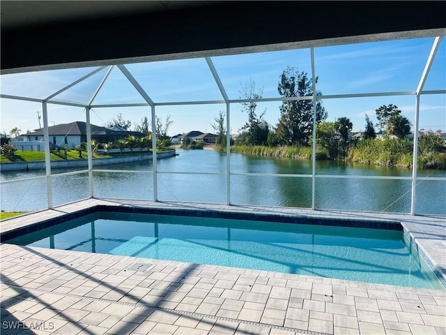 pool featuring glass enclosure, a patio, and a water view