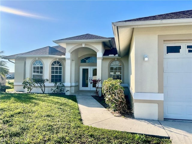 property entrance with french doors, a garage, and a yard