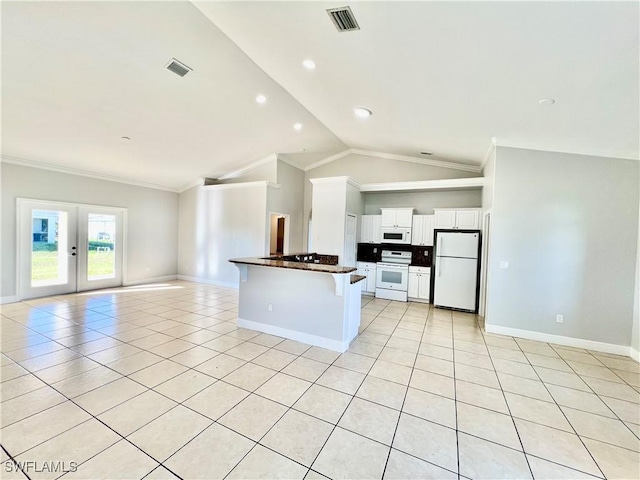 kitchen with light tile patterned flooring, a breakfast bar, white cabinets, and white appliances