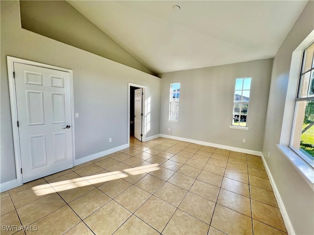 spare room featuring lofted ceiling and light tile patterned floors