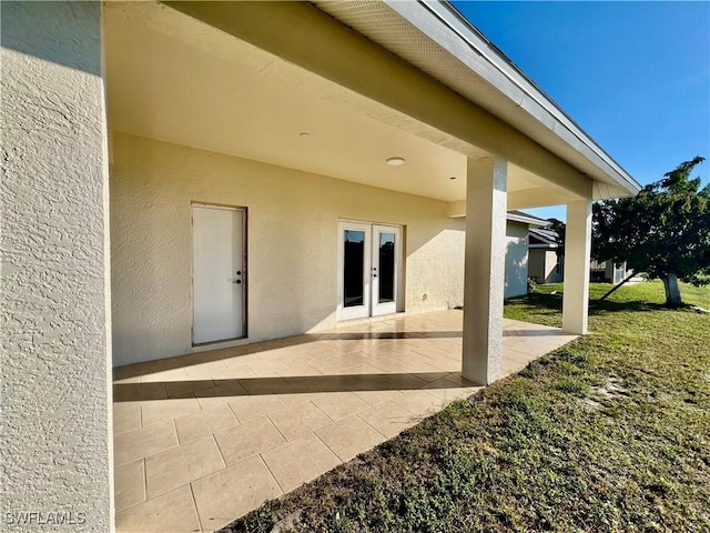 rear view of property featuring french doors, a lawn, and a patio area