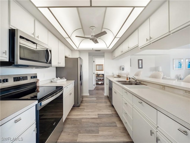 kitchen featuring sink, light wood-type flooring, ceiling fan, stainless steel appliances, and white cabinets