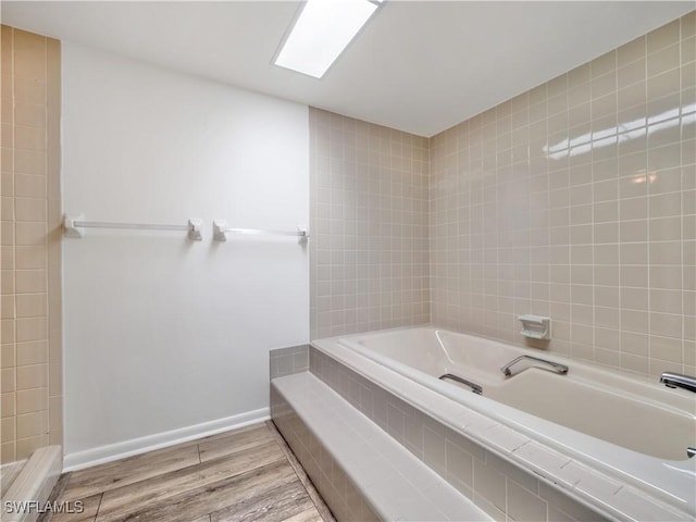 bathroom featuring tiled tub and hardwood / wood-style floors