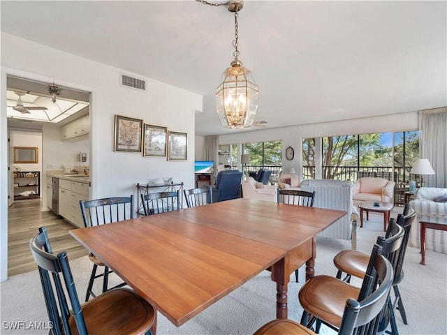 dining area featuring an inviting chandelier, sink, and light hardwood / wood-style flooring