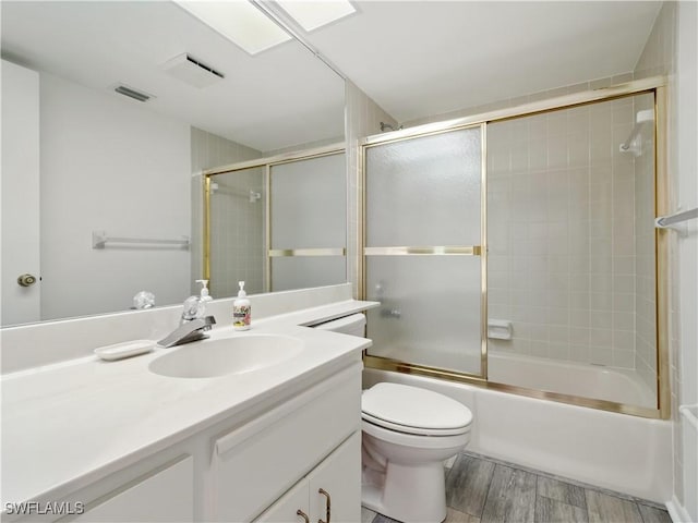 full bathroom with wood-type flooring, vanity, shower / bath combination with glass door, and toilet