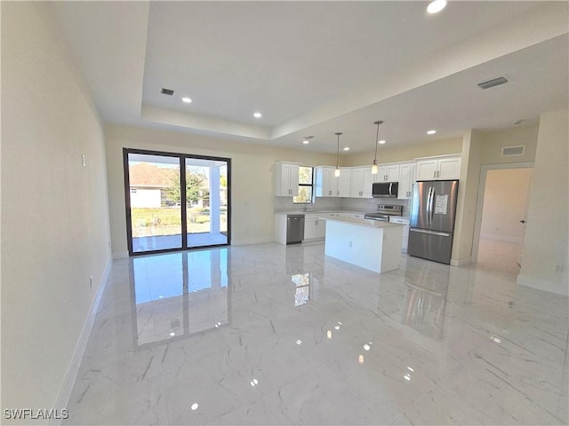 kitchen featuring white cabinetry, appliances with stainless steel finishes, a tray ceiling, a kitchen island, and pendant lighting