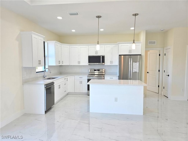 kitchen with decorative light fixtures, stainless steel appliances, a center island, and white cabinets