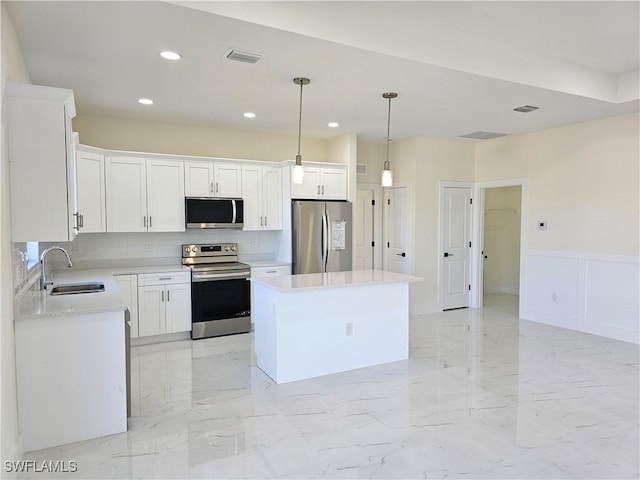 kitchen featuring pendant lighting, sink, white cabinets, a center island, and stainless steel appliances