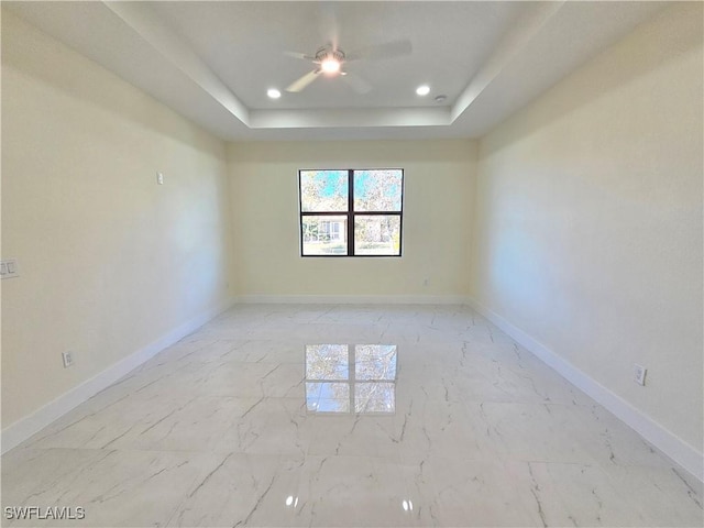 empty room featuring a raised ceiling and ceiling fan