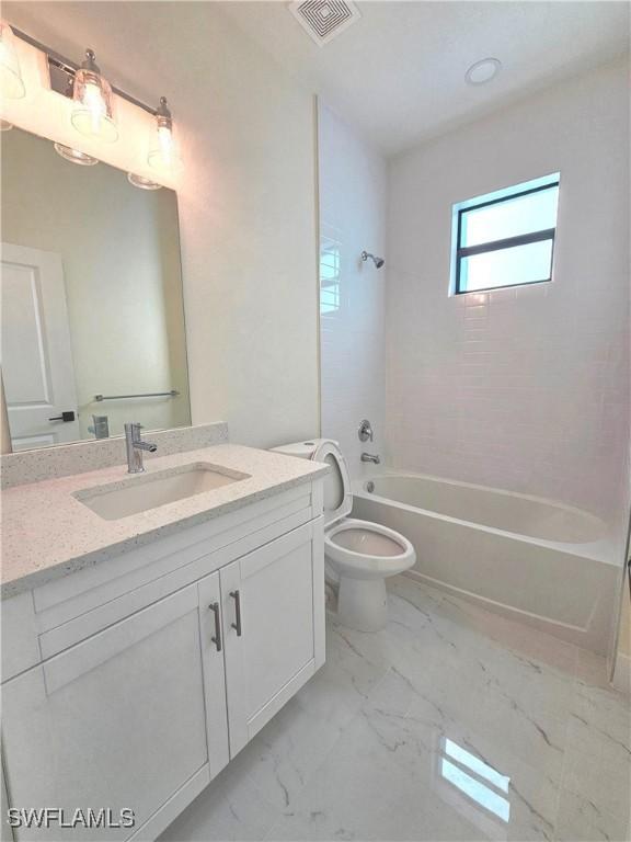 full bathroom featuring tiled shower / bath, vanity, and toilet