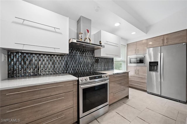 kitchen featuring stainless steel appliances, tasteful backsplash, light tile patterned flooring, and wall chimney exhaust hood