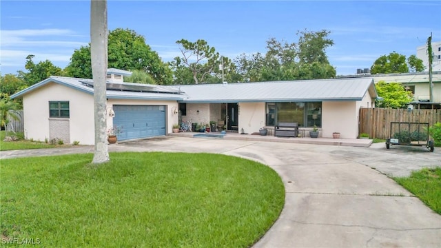 single story home with a garage, solar panels, and a front yard