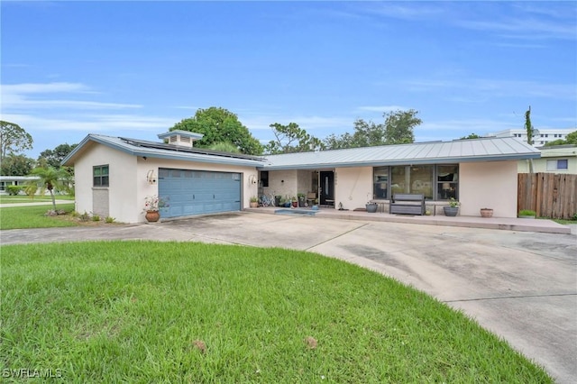 single story home featuring a garage, solar panels, and a front yard