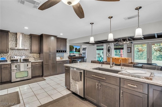 kitchen with dark brown cabinets, appliances with stainless steel finishes, wall chimney range hood, and pendant lighting