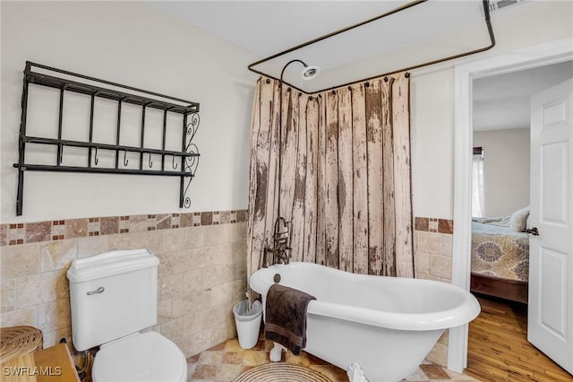 bathroom featuring shower / tub combo, toilet, tile walls, and wood-type flooring