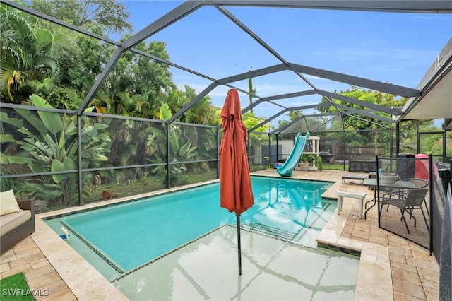 view of swimming pool featuring glass enclosure, a water slide, a patio, and a fenced in pool