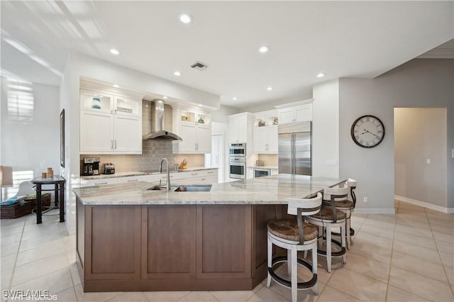 kitchen featuring a spacious island, wall chimney exhaust hood, sink, appliances with stainless steel finishes, and white cabinets