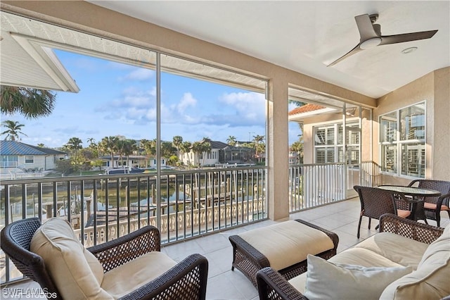 sunroom featuring a water view and ceiling fan