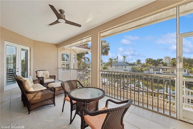 sunroom / solarium featuring ceiling fan and a water view