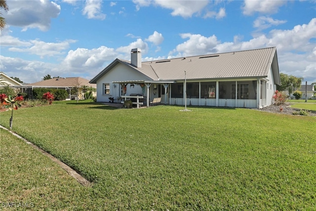 rear view of house with a yard and a sunroom