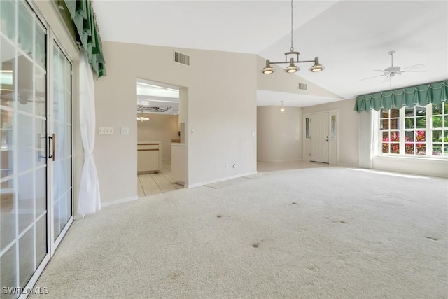 carpeted spare room with ceiling fan with notable chandelier and vaulted ceiling