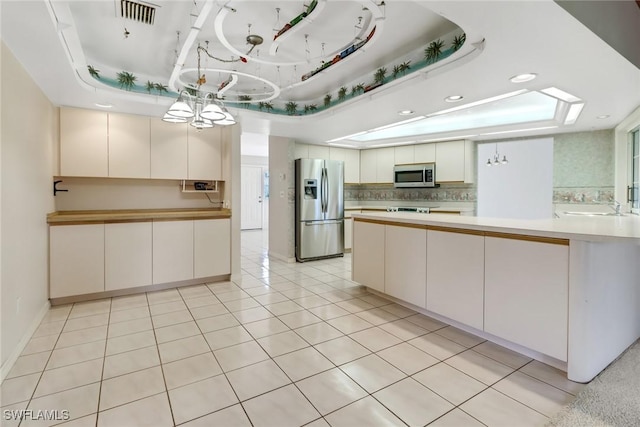 kitchen with sink, white cabinetry, a raised ceiling, stainless steel appliances, and backsplash