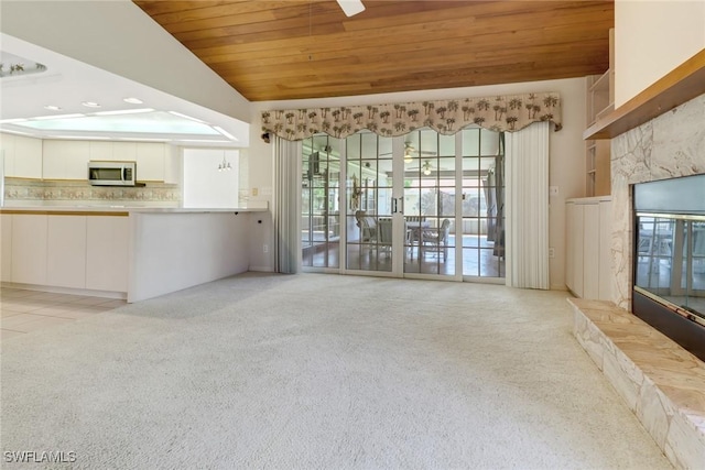 unfurnished living room featuring light carpet, vaulted ceiling, wooden ceiling, and a premium fireplace