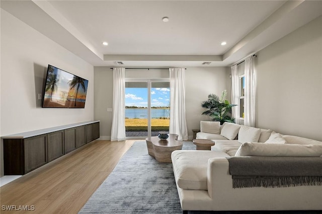 living room with a tray ceiling and light hardwood / wood-style floors