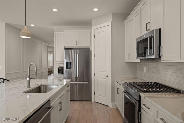 kitchen featuring sink, stainless steel appliances, hanging light fixtures, and white cabinets