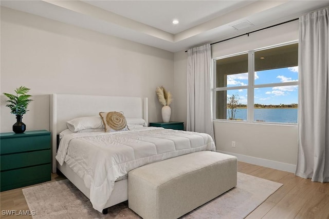 bedroom with a water view and hardwood / wood-style floors