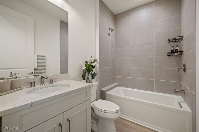 full bathroom featuring tiled shower / bath, wood-type flooring, vanity, and toilet