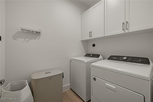 clothes washing area with cabinets, washer and clothes dryer, and light hardwood / wood-style floors