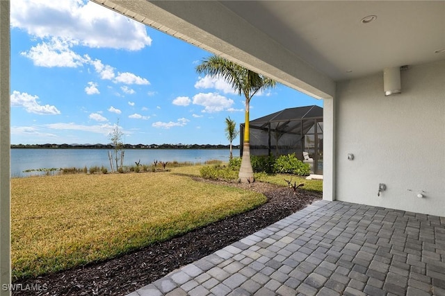 view of patio featuring glass enclosure and a water view