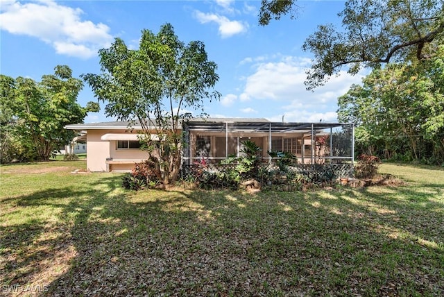 rear view of house featuring a yard, glass enclosure, and stucco siding