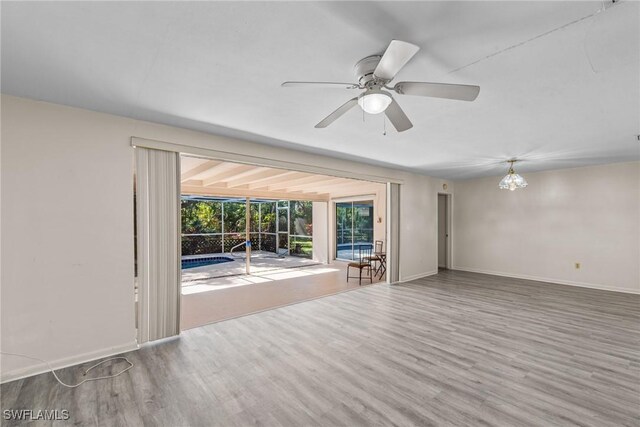 unfurnished living room featuring a sunroom, baseboards, and wood finished floors