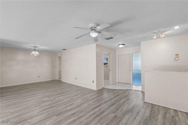 spare room featuring visible vents, wood finished floors, a ceiling fan, and baseboards