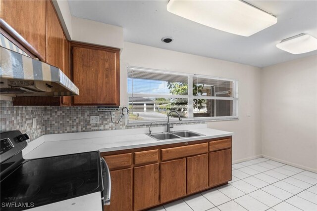 kitchen featuring light countertops, a sink, electric range, and ventilation hood