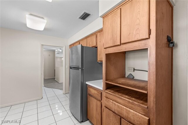 kitchen with light countertops, visible vents, freestanding refrigerator, light tile patterned flooring, and baseboards