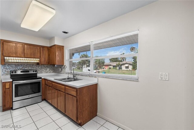 kitchen with brown cabinetry, a sink, stainless steel range with electric cooktop, under cabinet range hood, and backsplash