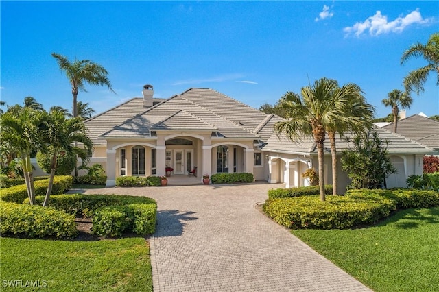 view of front of property with a garage, a tile roof, decorative driveway, french doors, and stucco siding