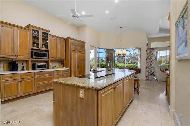 kitchen featuring a center island with sink, glass insert cabinets, brown cabinetry, and built in appliances