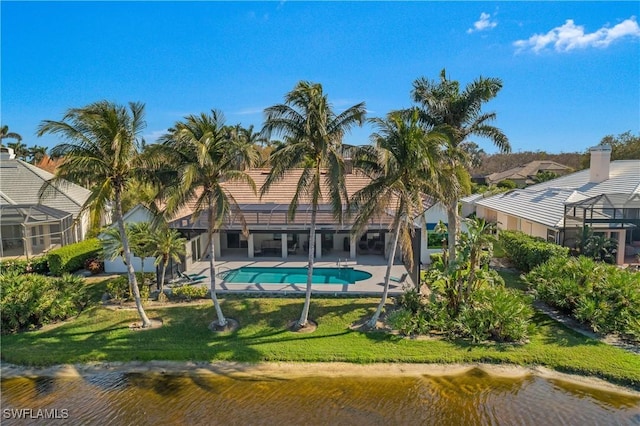 rear view of house featuring a yard, a patio, a water view, a lanai, and an outdoor pool