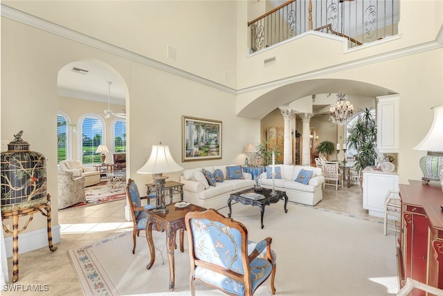 living room with light tile patterned floors, an inviting chandelier, a towering ceiling, ornamental molding, and ornate columns